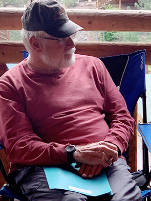 Bruce Hoover sitting in a camping chair with red shirt and hat